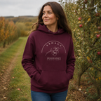 Woman wearing the Armagh Blossom maroon hoodie in an Armagh orchard