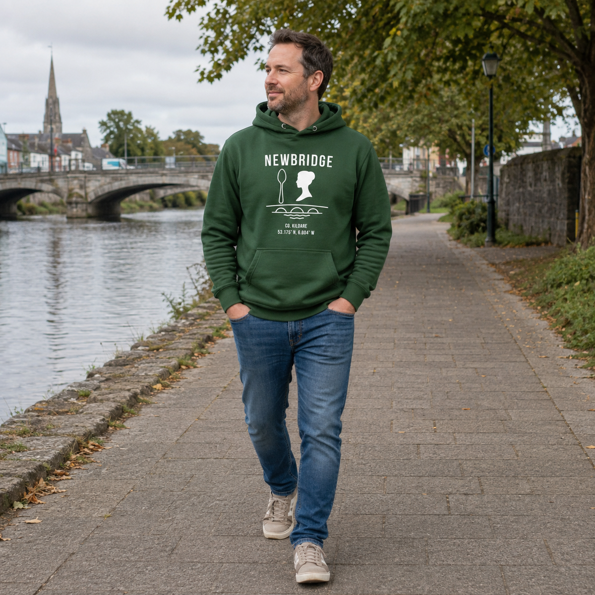 Man wearing the Kildare Newbridge forest green hoodie beside the River Liffey