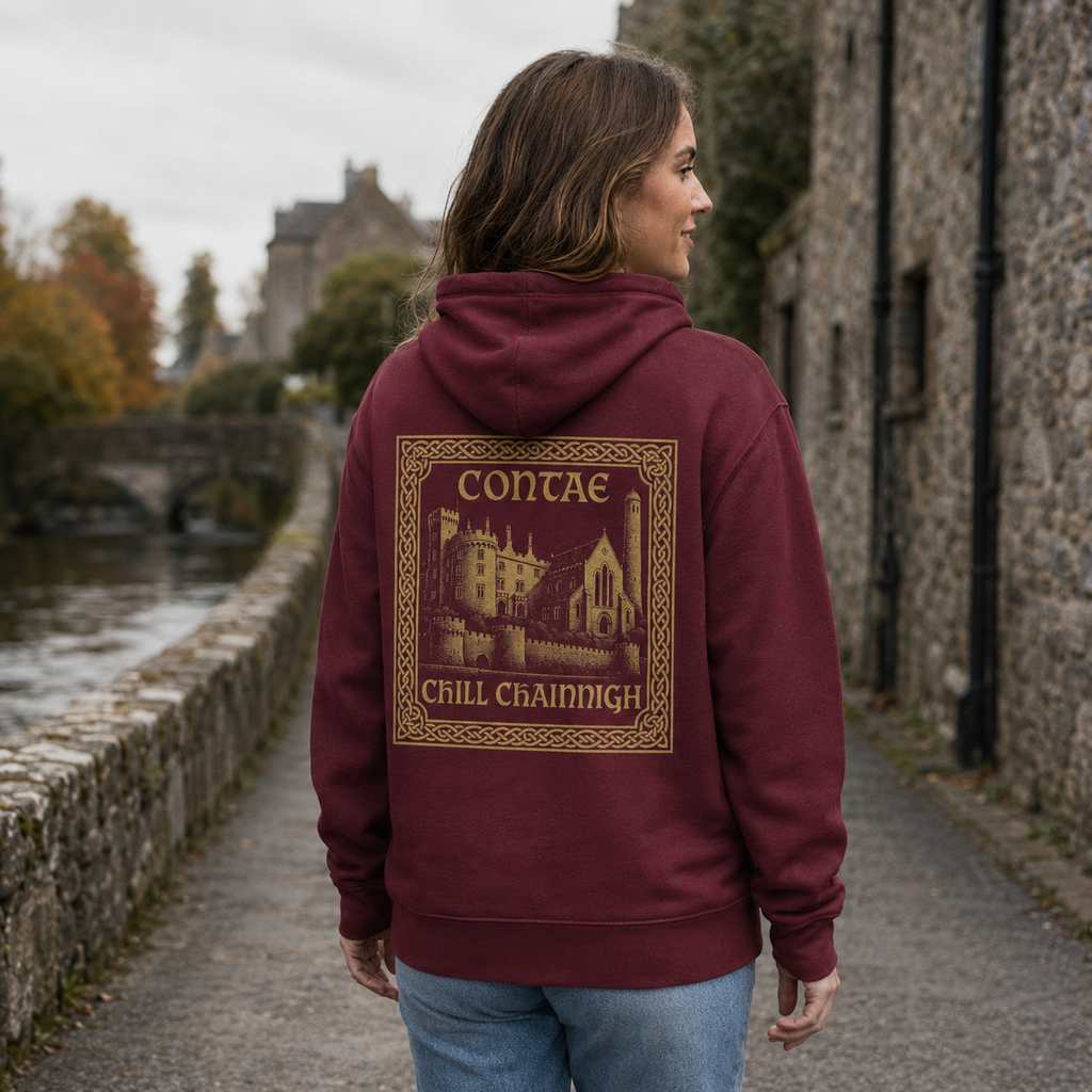 Woman wearing the maroon Kilkenny Heritage Hoodie from the back on a quiet medieval riverside lane