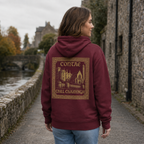 Woman wearing the maroon Kilkenny Heritage Hoodie from the back on a quiet medieval riverside lane